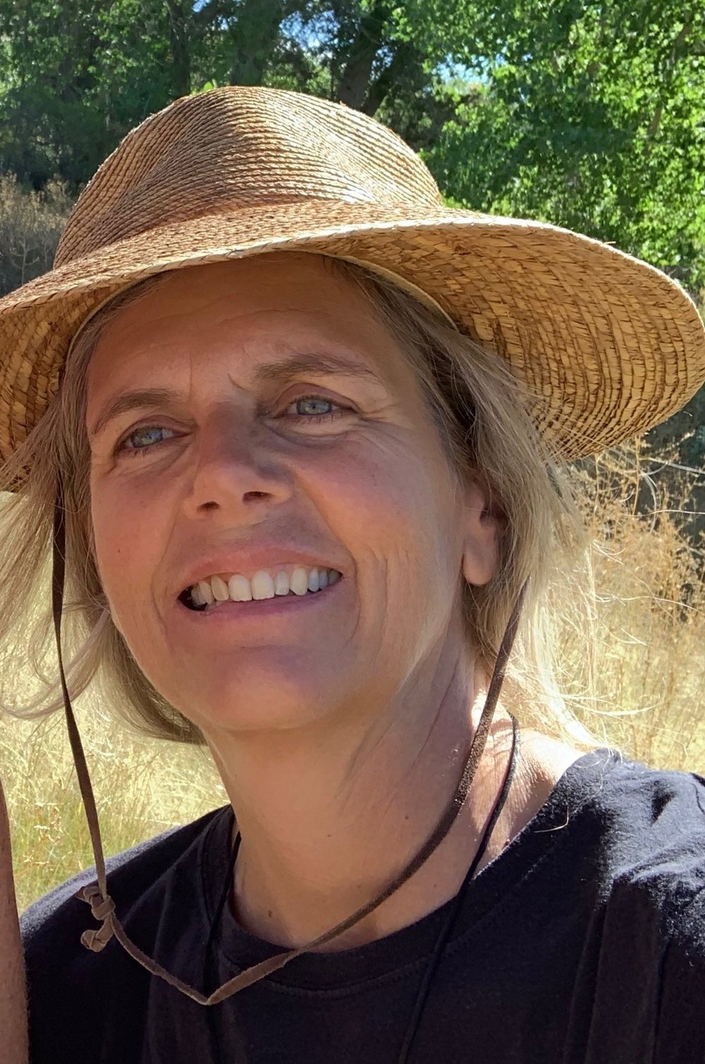 Cathy Robison smiling outdoors in a sun hat